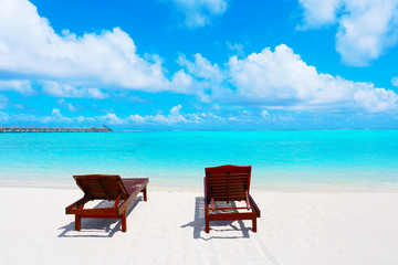 Fototapeta na wymiar Wooden sun loungers on sea beach in summer day