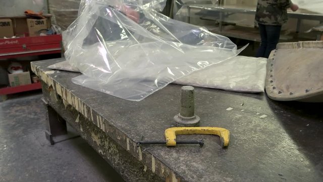 Plastic bag on workshop table. C-clamp on metal surface. Properties of polythene.