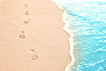 Human footprints on beach sand at resort in evening