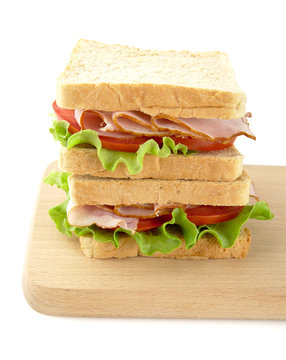 Sandwiches with lettuce,tomato,cold cuts on cutting board on white