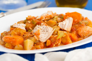 turkey stew with vegetables on white dish on wooden background