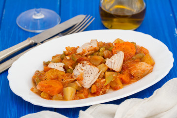 turkey stew with vegetables on white dish on wooden background