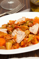turkey stew with vegetables on white dish on wooden background