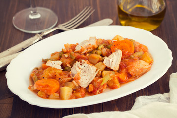 turkey stew with vegetables on white dish on wooden background