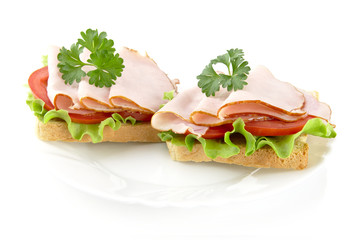 Sandwiches with lettuce,tomato,cold cuts with parsley on white