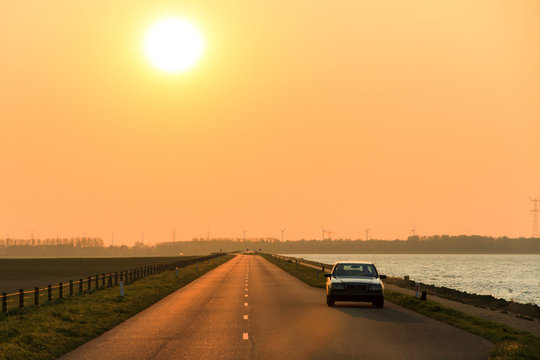 Mysterious car on the levee at sunset in the Netherlands
