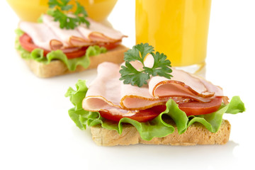 Toasts with cold cuts for breakfast with orange juice on white