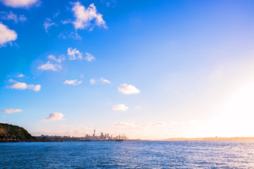 sunset on Auckland city’s skyline with the harbour, the ocean and some boats at the front