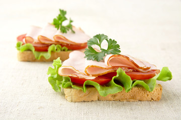 Toasts with lettuce,cold cuts on linen tablecloth