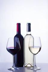 High glasses with red and white wine and two wine bottles