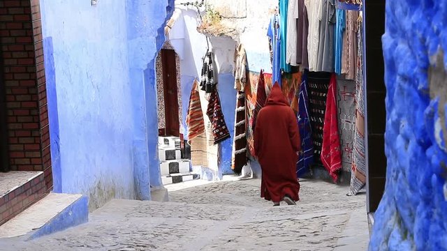 Walking people with traditional Arabic clothes in blue town Chefchaouen Chaouen / Morocco