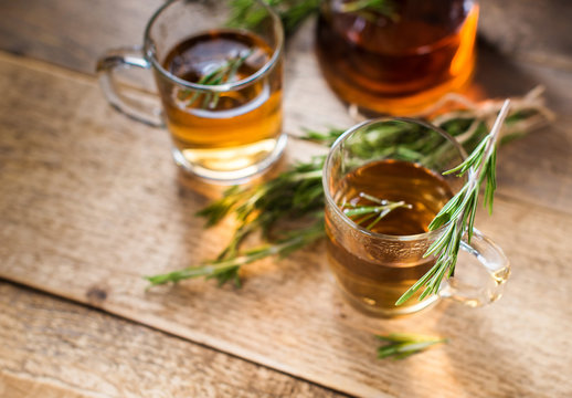 Herbal tea with aromatic rosemary on wood table