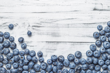 American blueberries scattered over white wooden background - obrazy, fototapety, plakaty