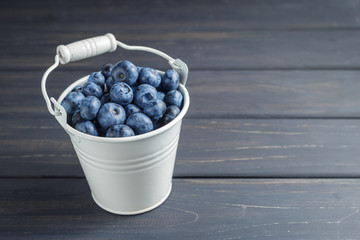 Blueberries in white bucket over black wooden background