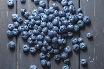 Heap of Blueberries scattered on black wooden background