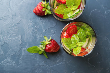 Cold and refreshing infused detox water with strawberry and cucumber in glass on black background. Top view.