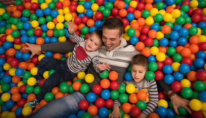 Fototapeta na wymiar Young dad with kids in a children's playroom