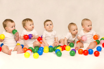 Five cute babies sitting among colorful balls. Party of newborns.