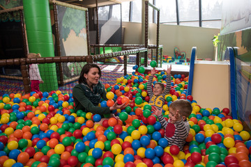 Young mom with her kids in a children's playroom
