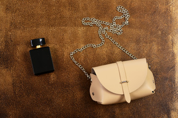 Leather purse and perfume bottle on brown suede background