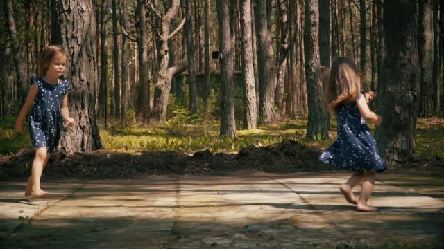Two lovely girls are dancing and running in the summer forest
