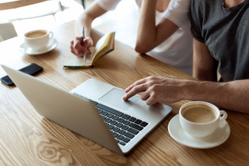 cropped shot of couple working together on laptop in cafe
