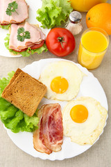 Fototapeta na wymiar Healthy lunchtime with two eggs,bacon with toast with juice on a plate
