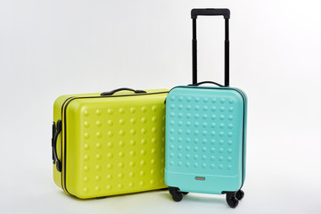 Close up of wheeled suitcases. Bright summer luggage, white background. Cases for journey.