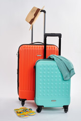 Summer hat on suitcase handle. Clothes and luggage for trip.