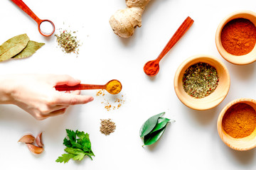 spices in wooden spoons on white background top view
