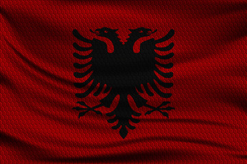 National flag of Albania on wavy fabric with a volumetric pattern of hexagons. Vector illustration.