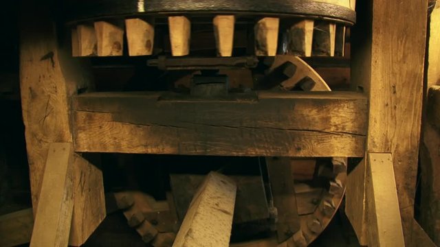 Cogwheels rotate in a 90-degree angle in an industrial corn mill. Sound of creaking and groaning of the timber