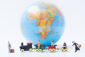 Tiny miniature model of travelers with luggage are sitting on the train with globe background using as travelling journey travel to destination background concept.