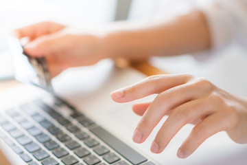 Hands holding a credit card and using laptop computer for online shopping