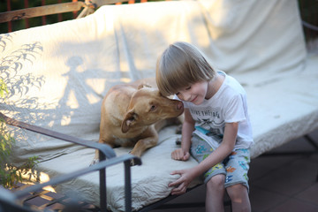 A child and a dog are playing on the couch in the open terrace of the house
