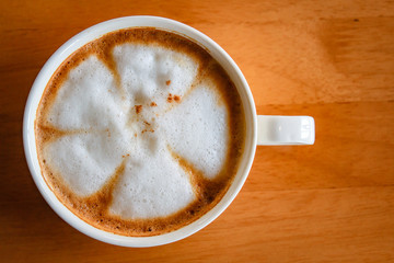 Hot cappuccino cup on wood table.