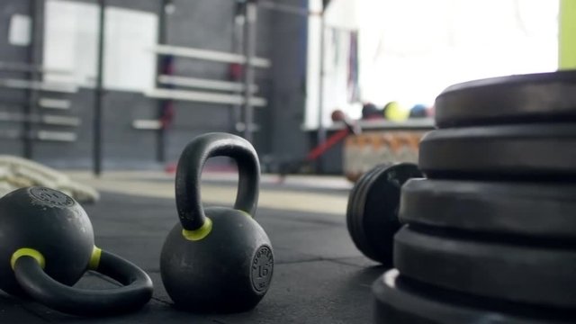 PAN of empty gym with kettlebells, weights and other sporting equipment lying on mat floor