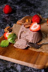 Italian dessert. Chocolate panna cotta with mint and strawberry. Dark wood background.