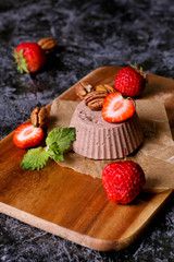Italian dessert. Chocolate panna cotta with mint and strawberry. Dark wood background.