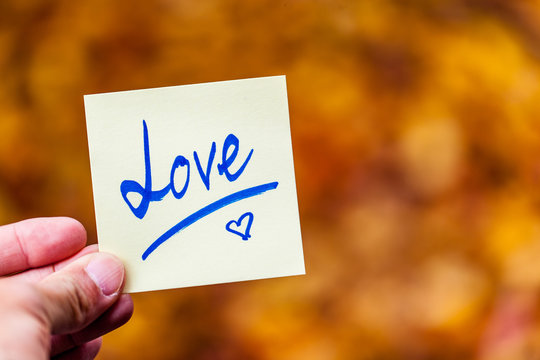 Love written in post it note in front of autumn leaves
