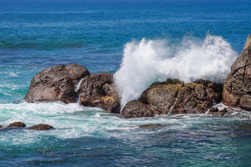 Splitting the sea wave on the stone shore