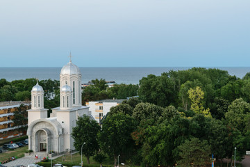 Fototapeta na wymiar Neptun Olimp, Romania - picture showing the local Christian church, green forest and the Black Sea.