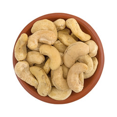 Top view of raw cashews in a small red clay bowl isolated on a white background.