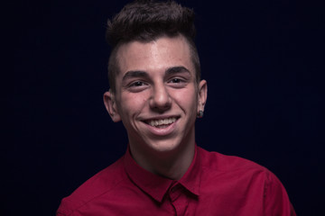 one teenager boy, red shirt, Caucasian, dark background, looking to camera, smiling