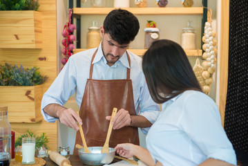 Husband with Pregnant woman cooking food in kitchen at home