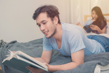 young loving couple reading a book on bedroom at home