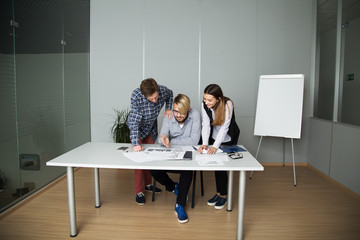 leader explains to the subordinates a new development strategy, one man sits and reads, another man and woman leaned over him and listen to him