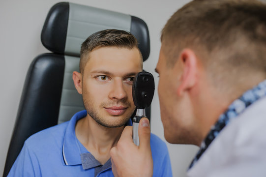 Young beautiful doctor/eye specialist/optometrist in an ophthalmologic clinic dooing to a patient eye test