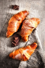 Chocolate croissant close up. Fresh and tasty croissant over wooden background for breakfast...