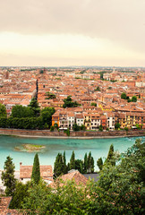 Fototapeta na wymiar Panoramic view to City of Verona with river at sunny day at sunset. Veneto region, Italy. Sunny summer day panorama, sky with clouds and famous european italian terracotta color houses, bird view.